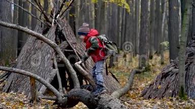 在秋林徒步旅行时，带背包和绳子的小<strong>童子</strong>军。 孩子看着森林里的一个小乳头。